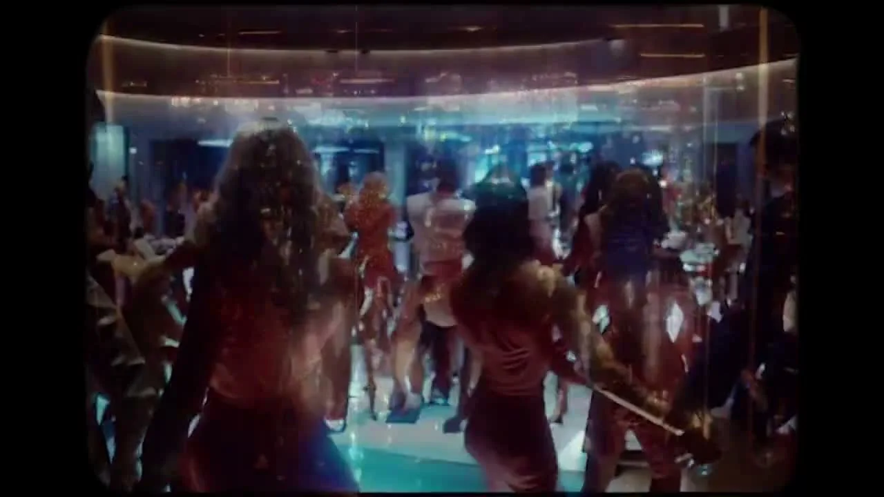 People seen from behind entering a nightclub with blue light and a bright curved ceiling.